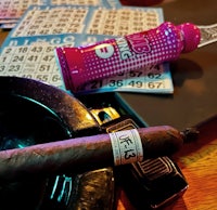 a cigar is sitting on a table next to a bottle of liquid